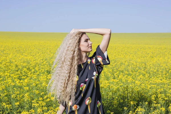 Enjoying life young blonde woman in a yellow blooming field. — Stock Photo, Image