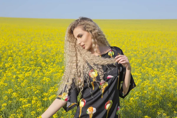 Summer joyful shot of a woman in a yellow booming field. — Stock Photo, Image