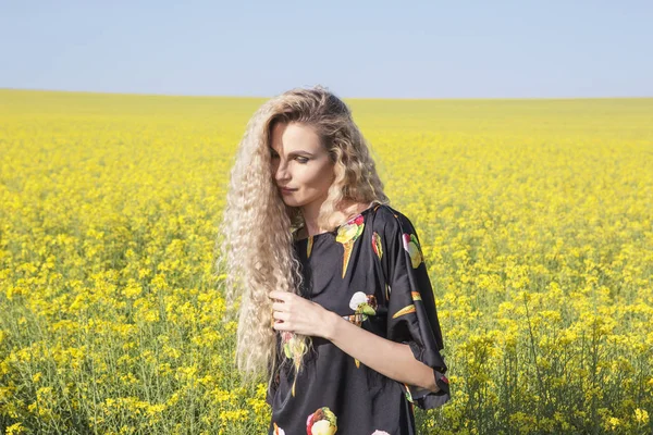 Romantic woman in a yellow blooming field. — Stock Photo, Image