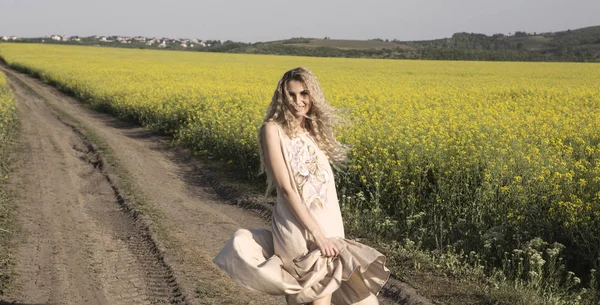 Gelukkig dansende vrouw in een geel veld achtergrond. — Stockfoto