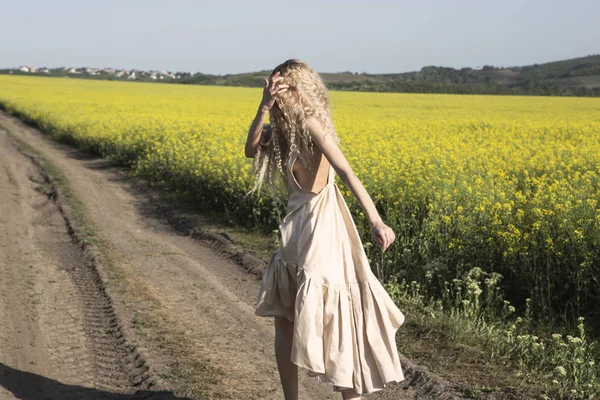 Running away and looking back blond girl. Country landscape. — Stock Photo, Image
