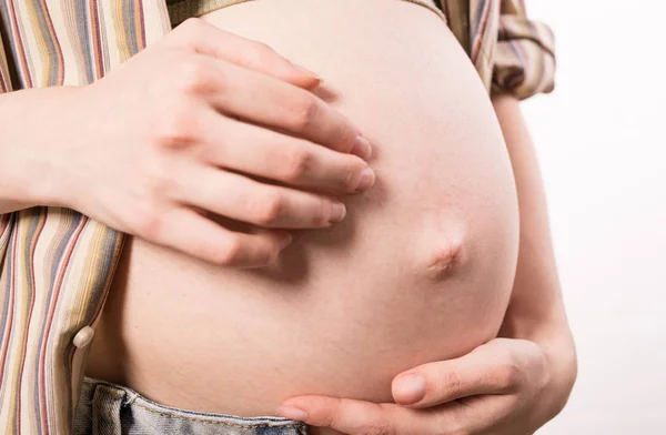 Close up shot of a pregnat belly with itching discomfort. Stock Picture