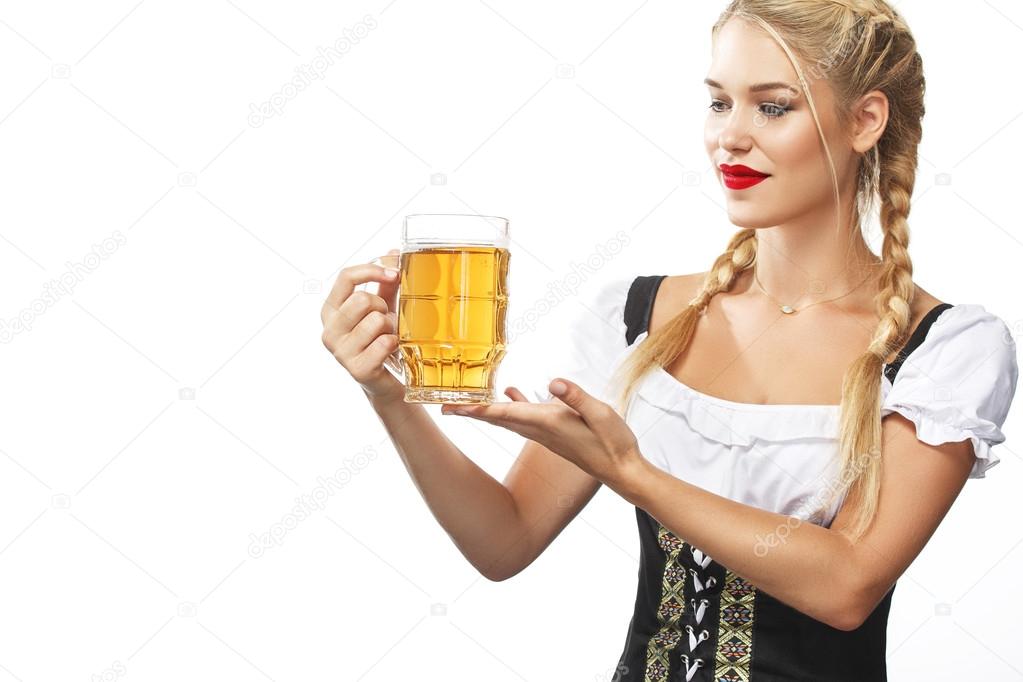 Young sexy Oktoberfest waitress, wearing a traditional Bavarian dress, serving beer mug isolated on white background.