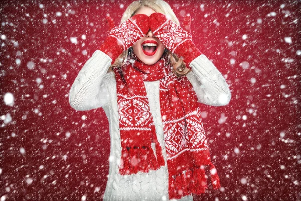 Gelukkig lachen blonde vrouw gekleed in slijtage wachten kerstcadeau, op rode achtergrond met sneeuw — Stockfoto