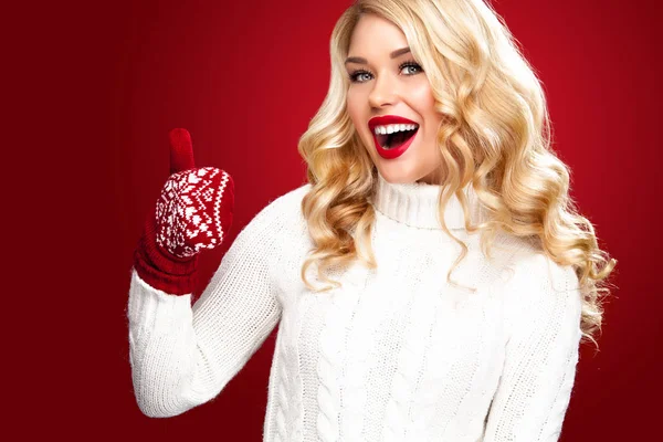 Feliz rindo mulher loira vestida com roupas de Natal com polegares para cima, isolado no fundo vermelho — Fotografia de Stock