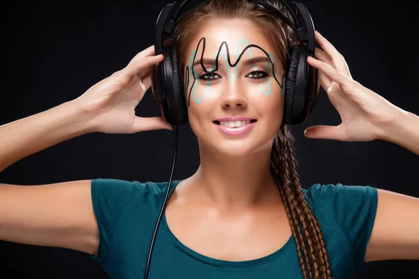 Modern young woman with art makeup enjoys listening to music in headphones. Positive emotions, leisure. Copy space. — Stock Photo, Image