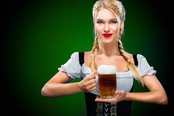 圣帕特里克节。年轻性感慕尼黑啤酒节服务员，穿着传统的巴伐利亚服装，与副本空间服务在蓝色背景上的大啤酒杯 — 图库照片