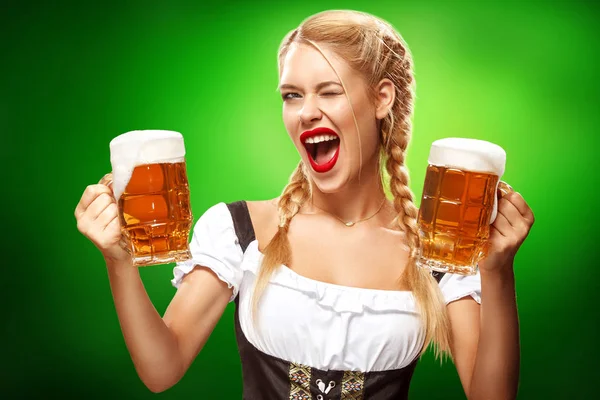 St Patricks Day. Mladá sexy Oktoberfest servírka, tradiční bavorské šatech, s kopií prostor sloužit velké pivní korbele na modrém pozadí — Stock fotografie