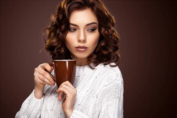 Красивая молодая женщина с чашкой кофе стоя на коричневом фоне — стоковое фото