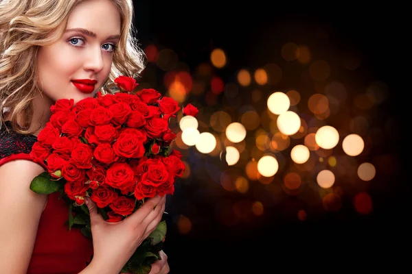 Beautiful blonde woman holding bouquet of red roses on bokeh background. Saint Valentine and International Womens Day, Eight March celebration. — Stock Photo, Image