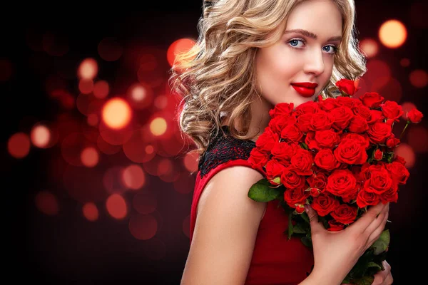 Beautiful blonde woman holding bouquet of red roses on bokeh background. Saint Valentine and International Womens Day, Eight March celebration. — Stock Photo, Image