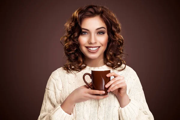 Belle femme souriante avec une tasse de thé sur le fond brun. Publicité café, espace de copie . — Photo