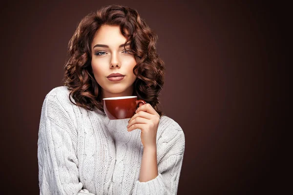 Красивая улыбающаяся женщина с чашкой чая на коричневом фоне. Реклама кофе, место для копирования . — стоковое фото