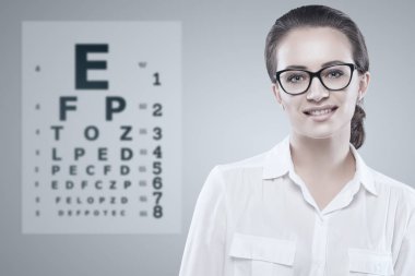 Snellen test grafik arka plan üzerinde ile gözlüklü kadın.