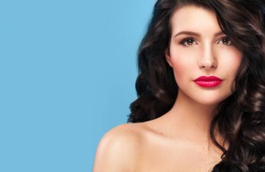 Uzun ve parlak dalgalı saçlı seksi kızı. Güzel model, mavi zemin üzerine Kıvırcık saç modeli.