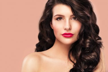 Uzun ve parlak dalgalı saçlı seksi kızı. Güzel model, turuncu zemin üzerine Kıvırcık saç modeli.