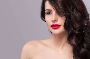 Uzun ve parlak dalgalı saçlı seksi kızı. Güzel model, gri arka plan üzerinde kıvırcık saç modeli.