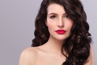 Uzun ve parlak dalgalı saçlı seksi kızı. Güzel model, gri arka plan üzerinde kıvırcık saç modeli.
