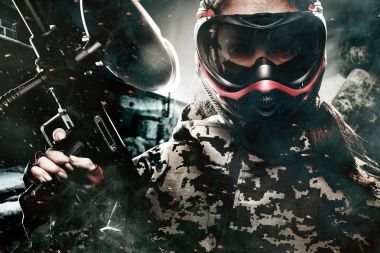 Ağır silahlı maskeli paintball asker sonrası kıyamet arka plan üzerinde. Reklam kavramı.