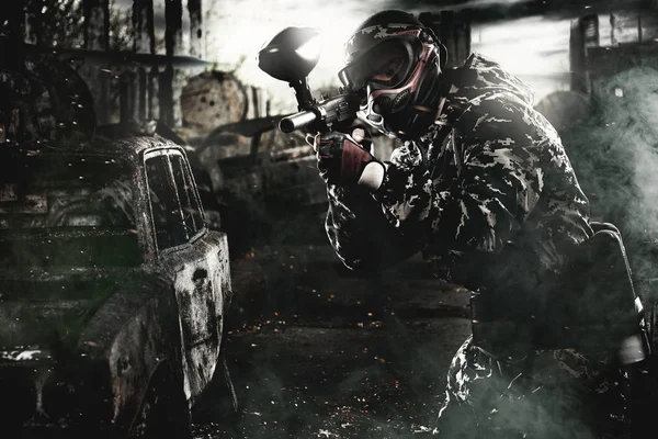 Heavily armed masked paintball soldier on post apocalyptic background. Ad concept. — Stock Photo, Image