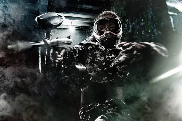 Heavily armed masked paintball soldier on post apocalyptic background. Ad concept. — Stock Photo, Image