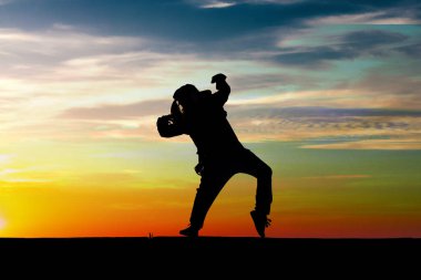 Küçük kız günbatımı arka plan üzerinde dans silüeti. Yaz çocuk.