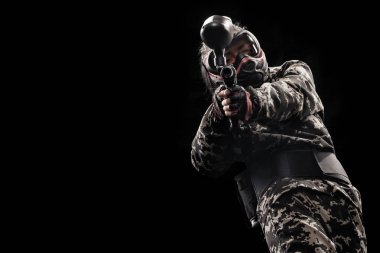 Siyah arka plan üzerine izole ağır silahlı maskeli asker. Paintball ve lasertag spor oyunları.