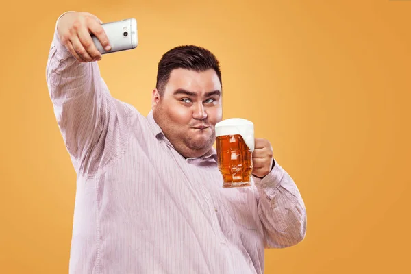スマート フォンで selfie 写真を作る黄色背景にビールではオクトーバーフェストで若いデブ男. — ストック写真