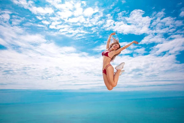 Uma bela mulher pulando, sobre o fundo do mar no verão. Conceito de viagem . — Fotografia de Stock