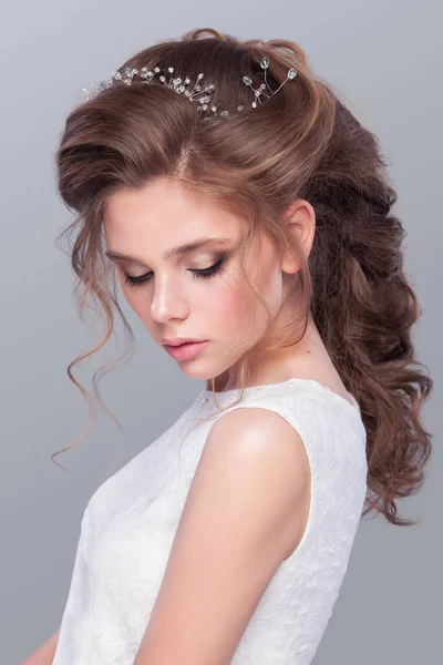 Hermosa novia con peinado de boda de moda - sobre fondo gris. Retrato de cerca de la joven novia hermosa. Boda. Estudio filmado con espacio de copia. Hermoso retrato de novia con velo sobre su cara — Foto de Stock