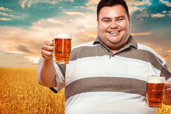 Young fat man at oktoberfest, drinking beer on yellow background. — Stock Photo, Image