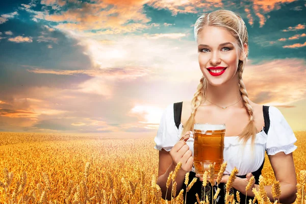 Mladá sexy Oktoberfest servírka, tradiční bavorské šatech, slouží velký pivní korbele na modrém pozadí. — Stock fotografie
