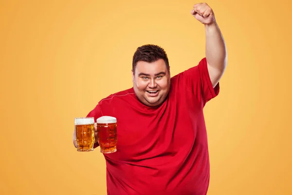 Tlustý muž šťastný oslava Oktoberfestu, pití piva na žlutém podkladu. — Stock fotografie