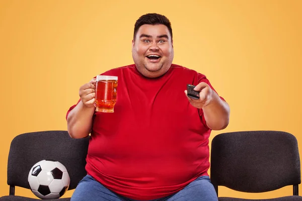 足球和体育乐趣 — — 快乐和胖人看电视，啤酒和足球球以黄色背景. — 图库照片