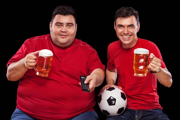 Two football funs - happy men watching sport on tv, taking beer and soccer ball on black background.