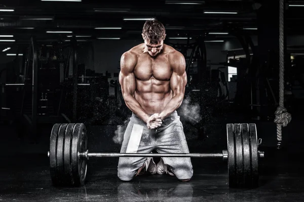 Muskulöser junger Fitnesssportler trainiert mit Langhantel im Fitnessstudio — Stockfoto