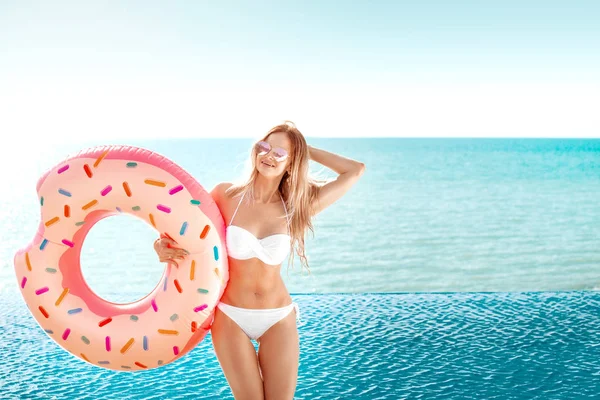 Vacanze estive. Godendo abbronzatura donna in bikini bianco con materasso ciambella vicino alla piscina . — Foto Stock