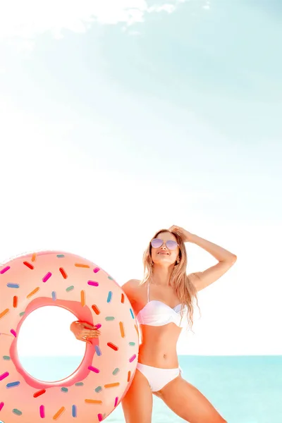 Vacanze estive. Godendo abbronzatura donna in bikini bianco con materasso ciambella vicino all'oceano . — Foto Stock