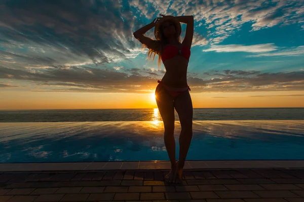 Zomervakantie. Silhouet van de dansende vrouw schoonheid op zonsondergang in de buurt van het zwembad met uitzicht op de Oceaan. — Stockfoto