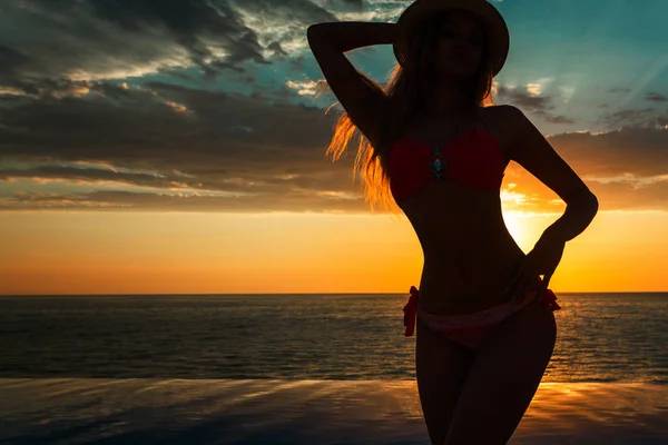 Vacaciones de verano. Silueta de mujer bailarina de belleza al atardecer cerca de la piscina con vista al mar . — Foto de Stock