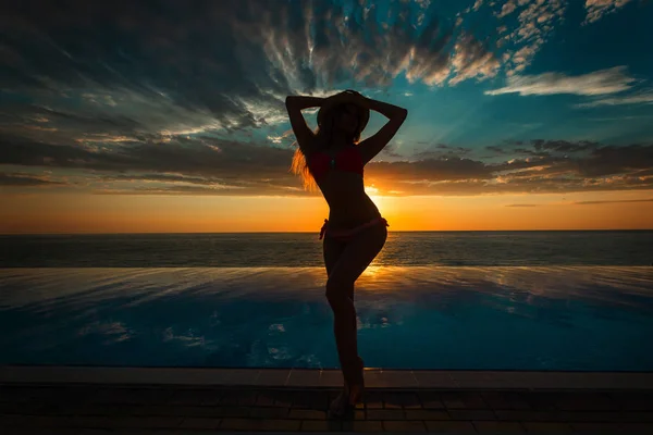 Vacaciones de verano. Silueta de mujer bailarina de belleza al atardecer cerca de la piscina con vista al mar . — Foto de Stock