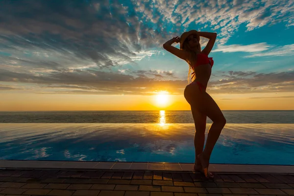 Літні канікули. Силует краси танцююча жінка на заході сонця біля басейну з видом на океан . — стокове фото