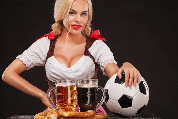 Sexy Oktoberfest dziewczynka - kelnerka, noszenie tradycyjny strój Bawarski, serwujemy duże kufle i przyjmowania piłki nożnej na czarnym tle. — Zdjęcie stockowe