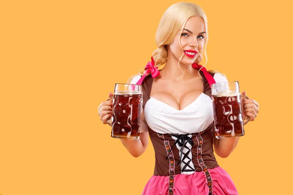 Junges sexy Oktoberfestmädchen - Kellnerin, in traditioneller bayerischer Tracht, serviert große Bierkrüge auf orangefarbenem Hintergrund. — Stockfoto