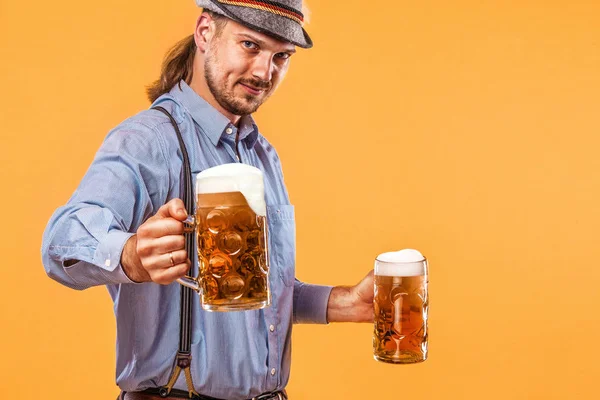 Podobizna muže Oktoberfest, tradiční bavorské oblečení slouží velký pivní korbele. — Stock fotografie