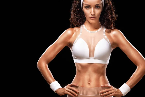 Sportlich schöne Frau mit lockigem Haar macht Fitness-Training auf schwarzem Hintergrund, um fit zu bleiben — Stockfoto