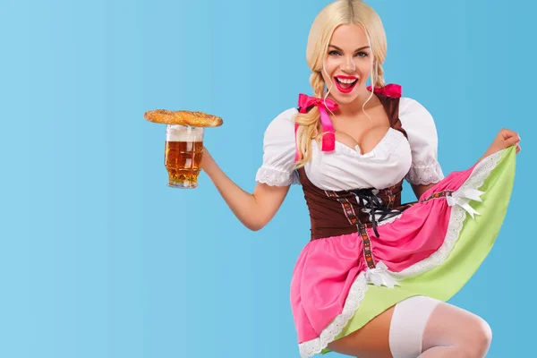 Fiatal szexi Oktoberfest lány - pincérnő, egy hagyományos bajor ruhát visel, szolgáló nagy sör bögrék a kék háttér. Másolja a hely. — Stock Fotó