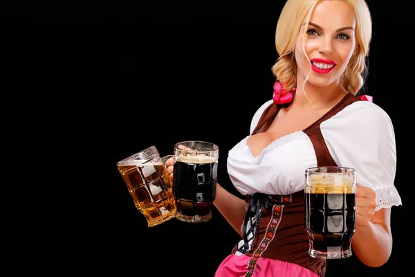 Retrato de cerca de Oktober fest girl - camarera, con un vestido tradicional bávaro, sirviendo tazas de cerveza grandes sobre fondo negro . —  Fotos de Stock