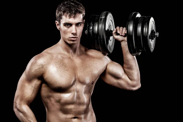 Athletic shirtless young sports man - fitness model holds the dumbbell in gym. Copy space fore your text. — Stock Photo, Image