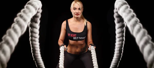 Battle ropes session. Attractive young fit and toned sportswoman working out in functional training gym doing crossfit exercise with battle ropes. Fitness and workout motivation — Stock Photo, Image